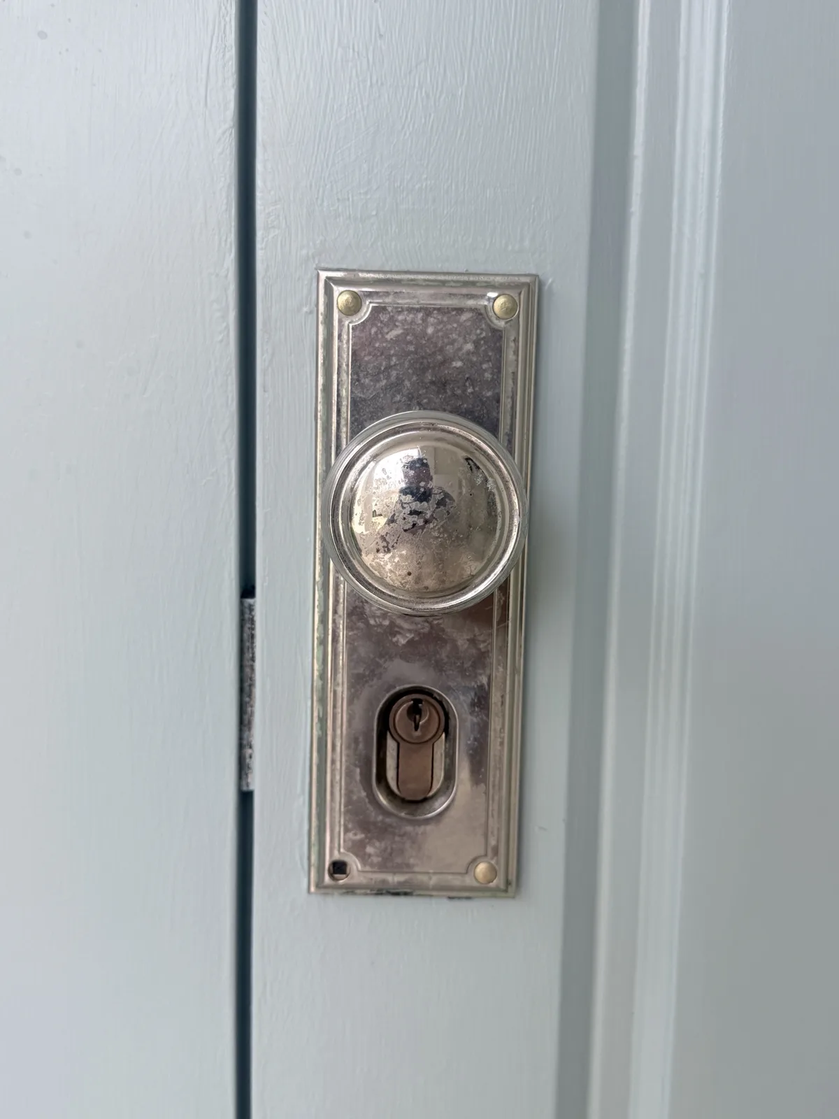 Worn nickel knob-and-plate entrance lock before replacement