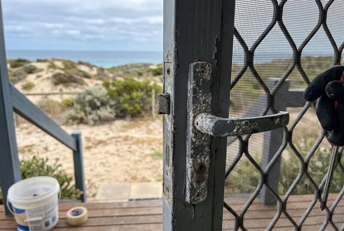 Salt-worn security screen door latch near the beach
